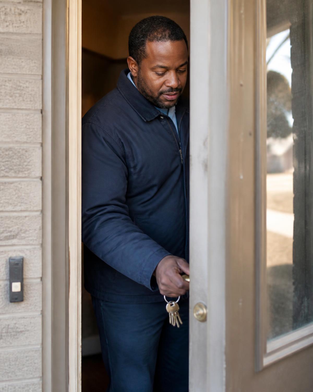A man unlocking the front door of a home
